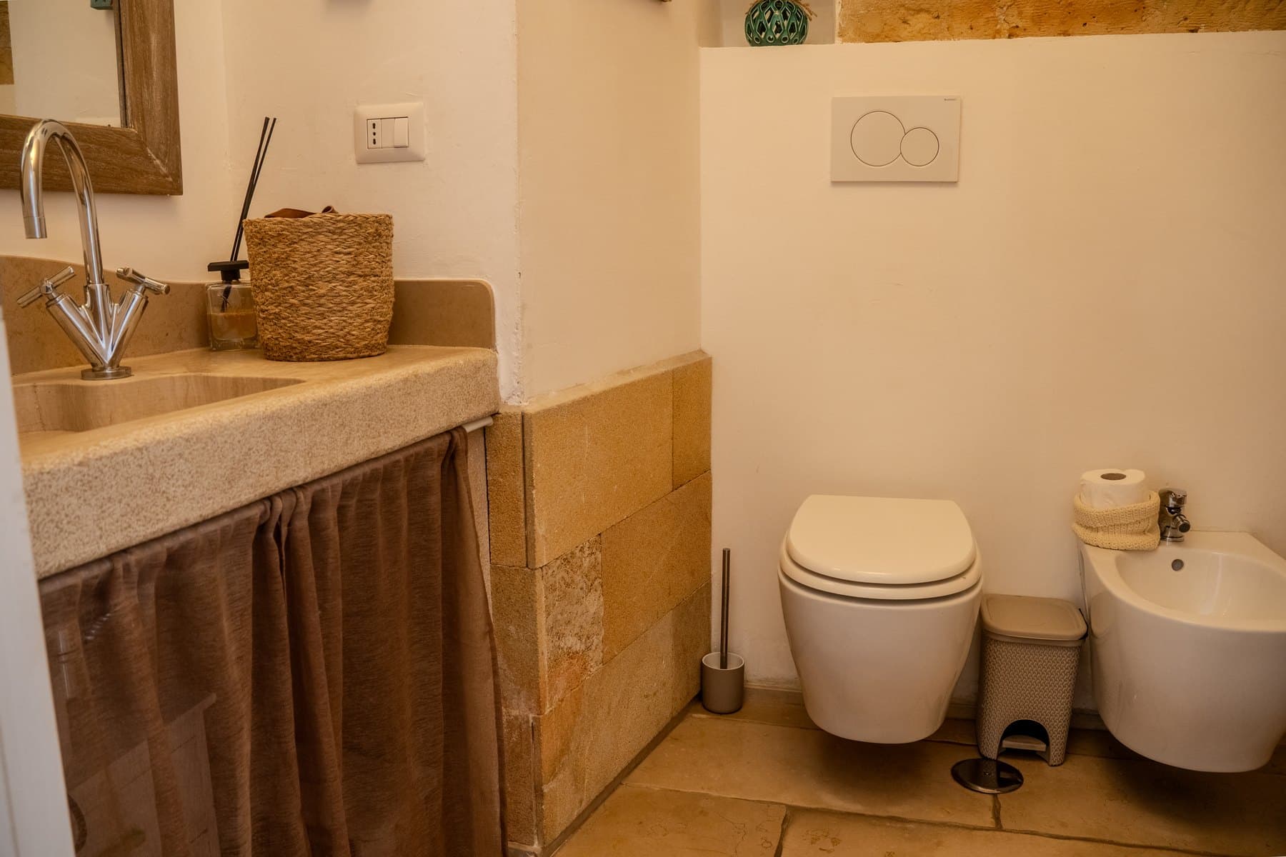 Il bagno completo con lavabo in pietra, sanitari sospesi e il rivestimento in tufo